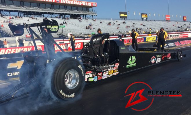 A drag racer driving a drag car with smoke coming out of it.