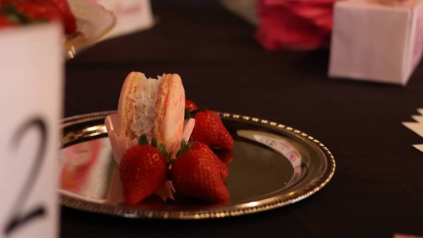 A plate with strawberries and macaroons on it.