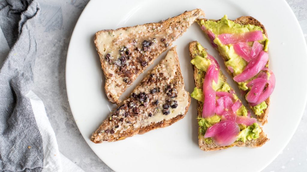 Two slices of toast with avocado and guacamole on a plate.