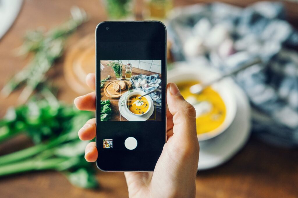 A person taking a photo of food on a smartphone.