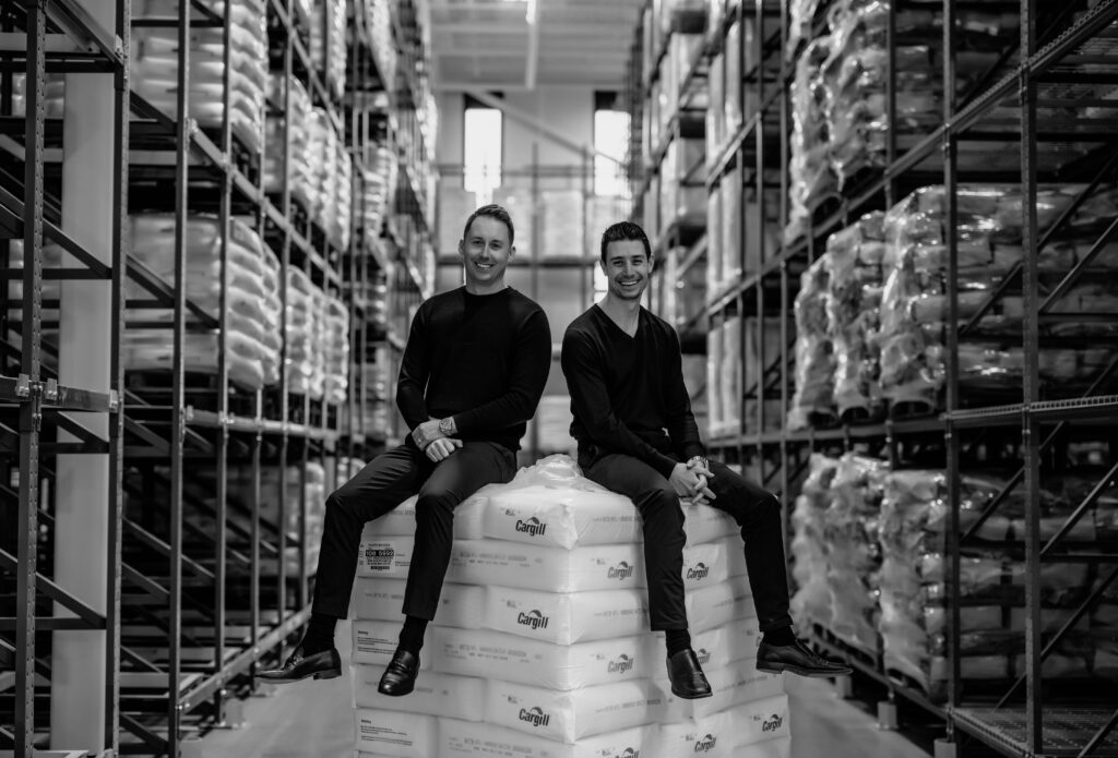 Two men sitting on top of boxes in a warehouse.
