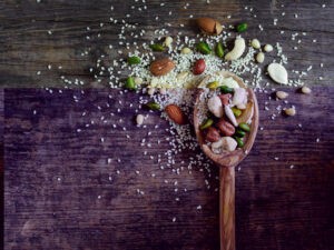 Plant-Based Ingredients: A spoon filled with nuts and seeds on a wooden table.